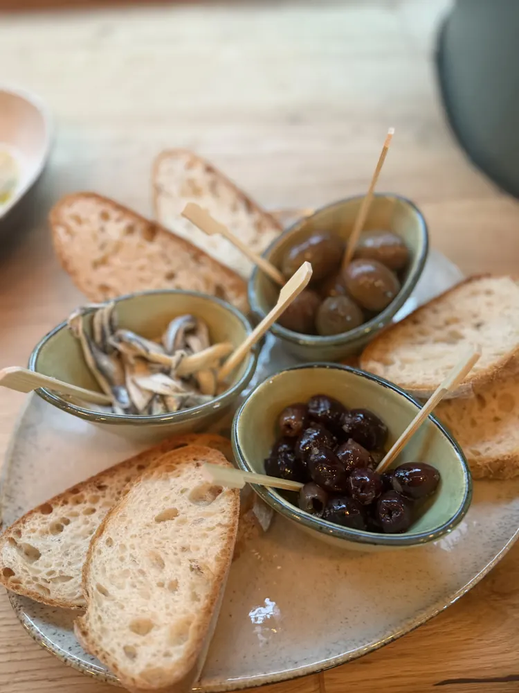 Antipasti-Teller mit Oliven, Sardellen, eingelegten Peperoni und geröstetem Brot