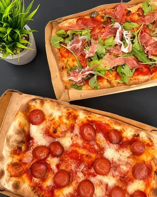 Zwei Pinsen, eine mit Salami, eine mit Rucola und Schinken