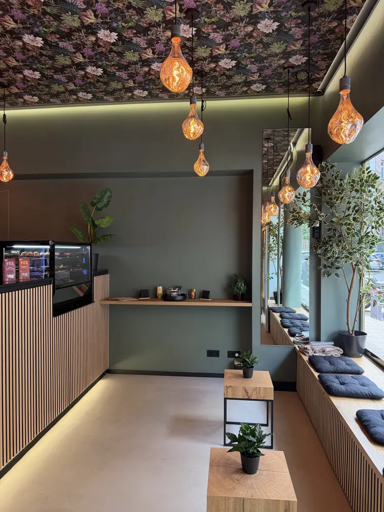 Sitzbereich mit Holzbank, Kissen, kleinen Beistelltischen und Blumentapete an der Decke
